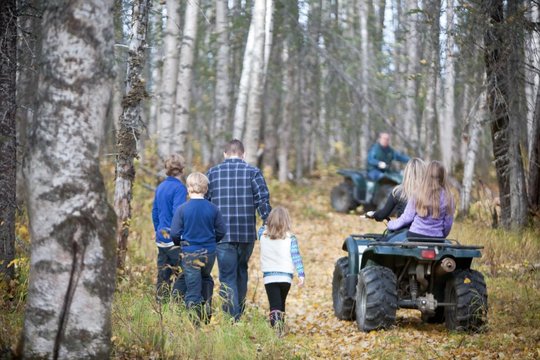 Family walking a wooded trail with a four-wheeler