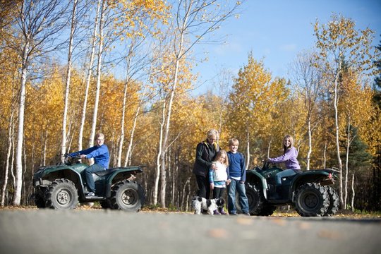 Family with four-wheelers on a birch-lined road